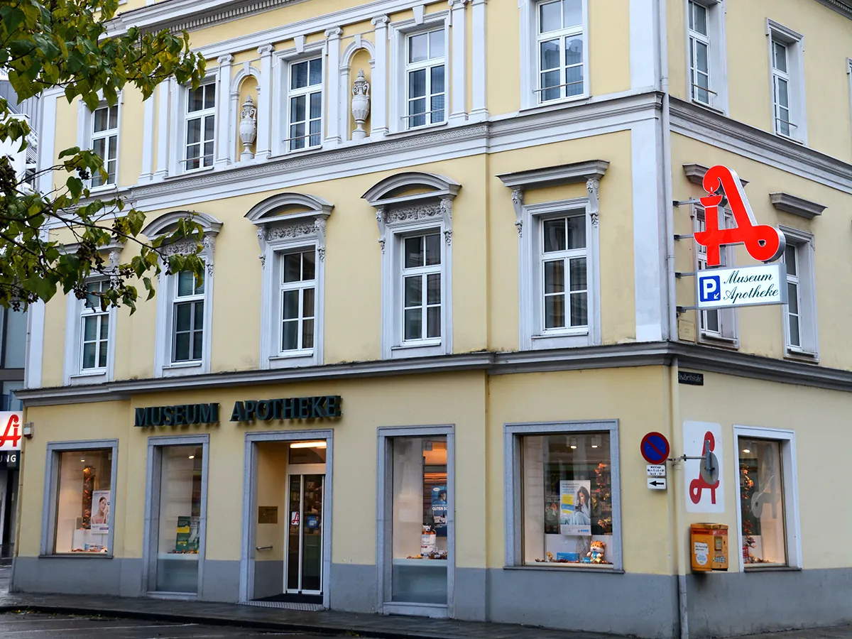 Gelbes Eckhaus Elisabethstraße 1 in Linz mit dem Schriftzug „Museum Apotheke“ über dem Eingang und rotem Apotheken-A