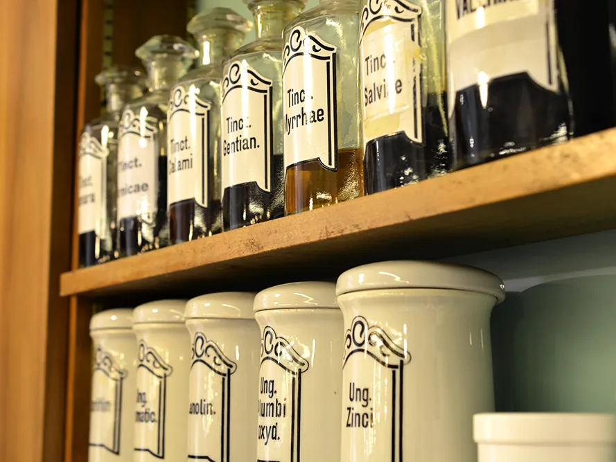 Historische Standgefäße aus Glas und Porzellan mit Tinkturen und Salben im Regal der Museum-Apotheke